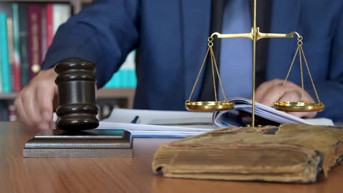Man Writes Next to Gavel and Scales of Justice