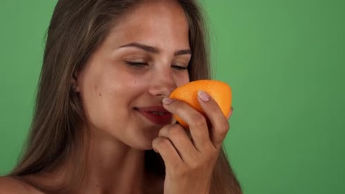 Woman Smells Fresh Orange Half in Close Up