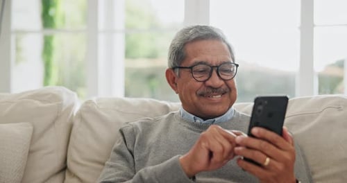 Senior Man Using Smartphone on Couch Indoors