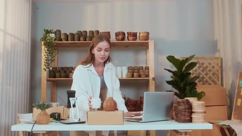 A young pretty woman entrepreneur checking and packaging craft products