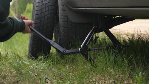 Jack Lowering a Car on the Side of the Road to Change a Tire