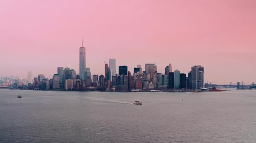 A wide-angle shot of Manhattan's skyline at sunrise with a pink sky backdrop, capturing high-rise sk
