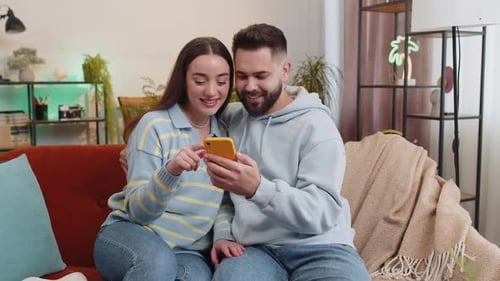 Couple Celebrates Success on Cell Phone Indoors