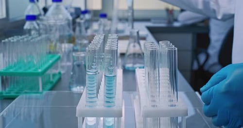 Close Up of Chemist Taking Liquid with Pipette From Glass Flask Pouring Into Test Tubes