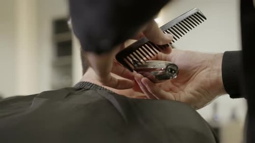 Professioneller Friseur, der Haare mit elektrischem Haarschneideclip schneidet