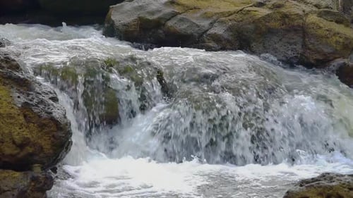 Slow motion shot of flowing water stream on rocky river in nature,close up