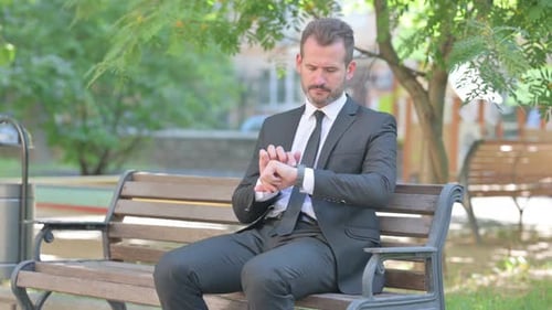 Man in Suit Checking Smart Watch on Park Bench