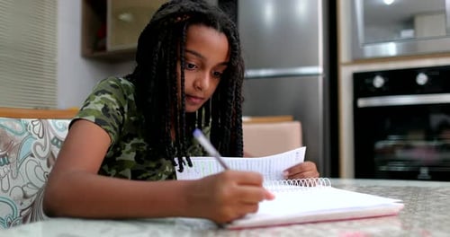 Girl Doing Homework at Table Indoors Writing Notes
