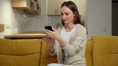 Woman Using Smartphone on Couch at Home