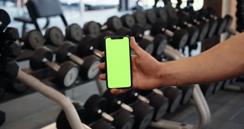 Male Hand with Smartphone in Gym Fitness Application Results Green Screen