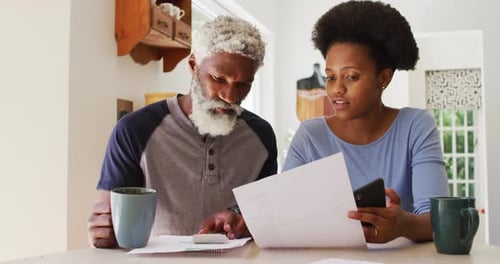 Pareja afroamericana tomando café y pagando facturas en la cocina