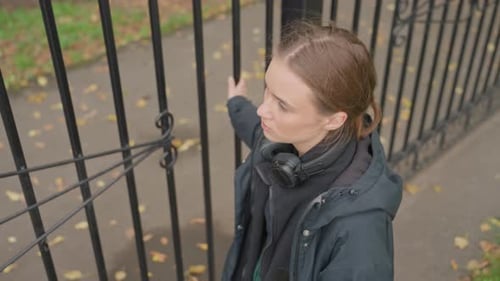 Person Wearing Headphones Gazes Thoughtfully Into Cloudy Park Surroundings Contemplative Woman with