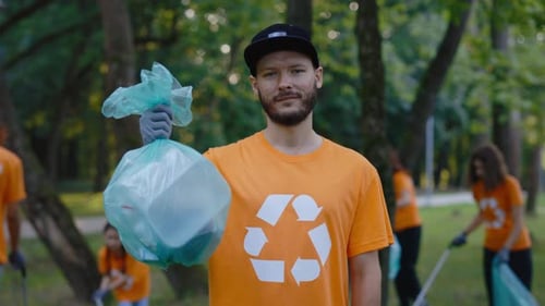 Man Holds Trash Bag During Park Cleanup