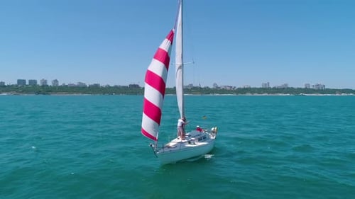 Yacht sailing on sea. Red and white sails on a boat at windy day.