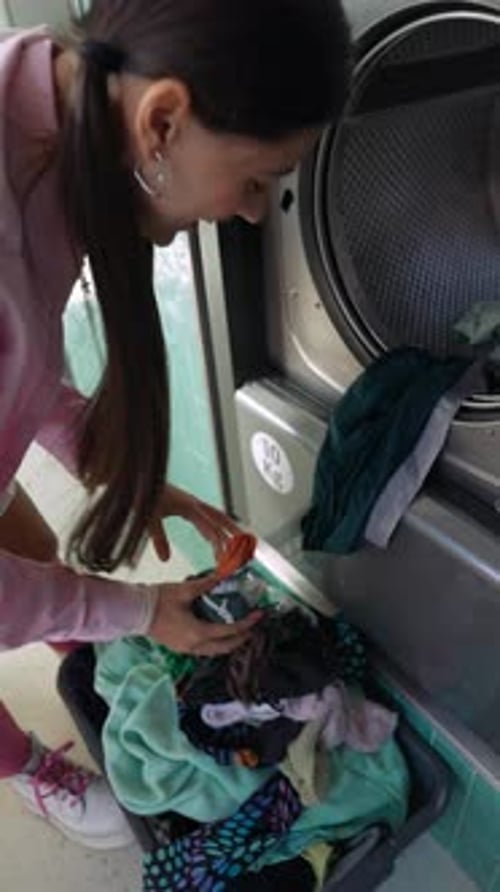 Woman Loading Clothes into a Washing Machine