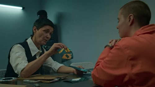 Woman Interviewing Handcuffed Suspect in Interrogation Room