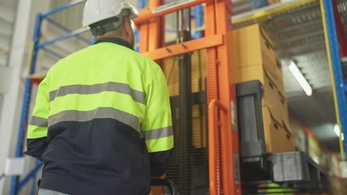 Back of warehouse worker man stand to control cargo truck during his coworker carry box out