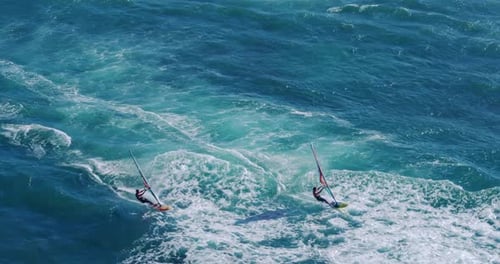 Aerial view of windsurfers gliding across blue ocean,