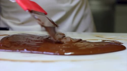 Tempering melted Chocolate on natural Stone with spatula Close-Up. Production Of Chocolates
