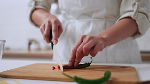 The Process Of Slicing Green Chili Peppers, The Chef Cuts A Small Chili Pepper With A Ceramic Knife