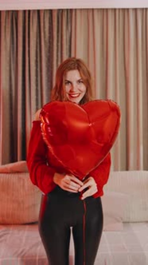 Woman Holds Red Heart Balloon in Bedroom