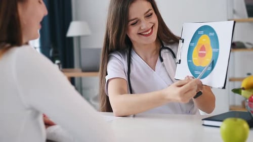 Holding illustration with nutrition data. Young woman have a consultation by female nutricionist i
