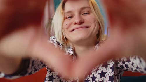 Woman Makes Heart Shape with Hands Indoors