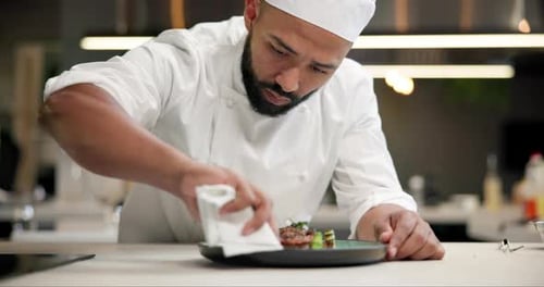 Chef, food and man plating in kitchen cleaning edge for gourmet meal at luxury diner