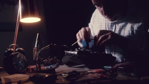 Man Disassembles an Electropneumatic Device with a Screwdriver and Other Tool Men's Work in the