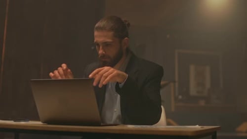 Bearded Man Working Late at Desk on Laptop