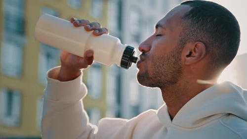 Man Drinking Water Bottle in Urban Sunlight