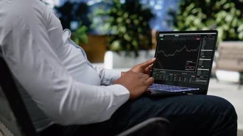 Black Man Navigating Stock Trading Indicators Online on Laptop