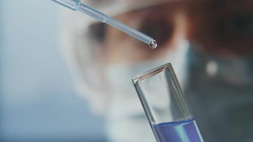 Close Up of Lab Technician Dispensing Liquid from Pipette into Test Tube