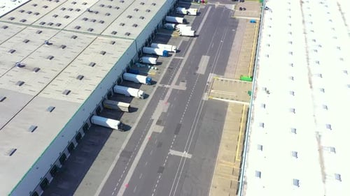 Luftbild eines Sattelschleppwagens mit Frachtanhängern, der auf Lagerhausrampen zum Be- und Entladen steht