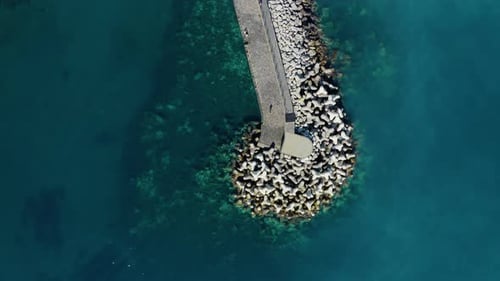 Aerial View of People Walking on Coastal Breakwater Pier with Tetrapod Wave Barriers in Vibrant