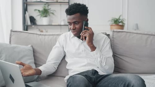 Young Adult Working with Laptop and Talking on Phone