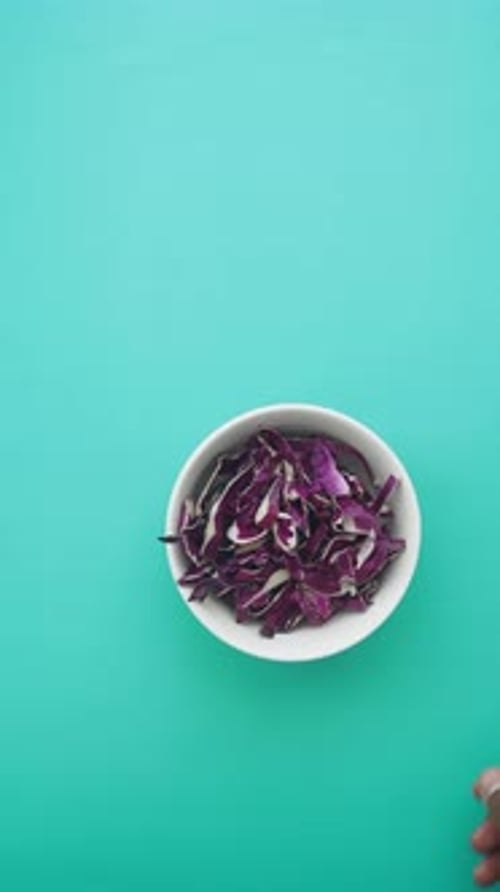 Freshly Shredded Purple Cabbage in a Bowl on a Vibrant Background