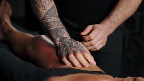 Woman Receiving Leg Massage from Tattooed Man