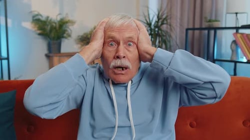 Man Holding Head With Shocked Expression Indoors