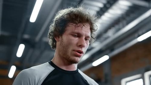 Tired smiling kickboxer relaxing at gym after successful workout in fitness center
