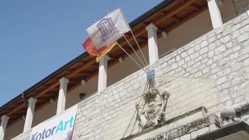 Blazon and Flaggs of Unesco, Kotor and Montenegro over the sea gate entrace of the city walls and ol