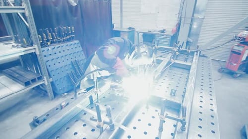 Welder in Protective Gear Working on Metal Frame