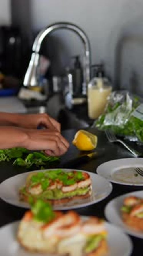 Person Garnishing Shrimp Open Faced Sandwiches with Greens
