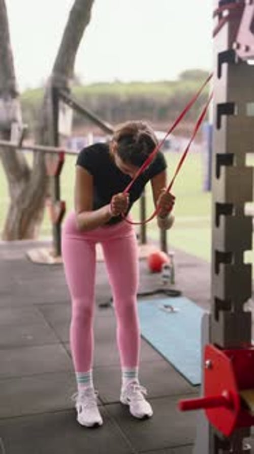 A Young Woman Engaged in a Physical Workout Session with Resistance Bands at a Local Gym