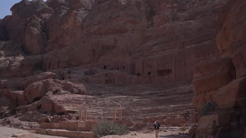 Little Petra Jordan. Lonesome Man Walking Under Carved Caves in Sandstone Cliffs on Hot Day, Wide Vi