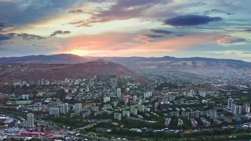 Aerial view of Tbilisi urban skyline under sunset sky