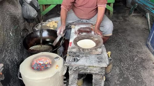 Shot of an Indian man making Rotis on traditional Indian stove at a roadside stall in Kolkata, India