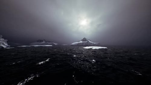 Flying Over Dark Icy Ocean with Mountains Under Stormy Sky