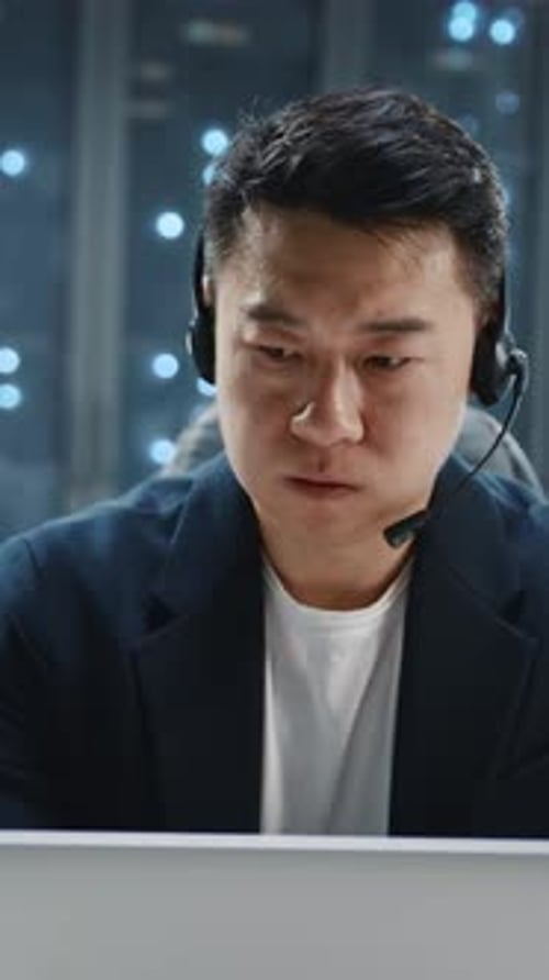 Man in Office Wearing Headset Working on Laptop