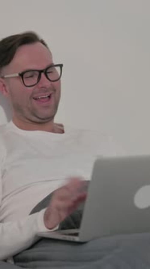 Man Video Calling on Laptop While Lying in Bed